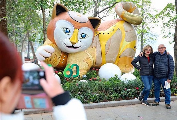 Foreign tourists pose for a photo besides a statue of the cat, the symbol of Lunar New Year 2023, in Hanoi. Photo: VNA Foreign tourists pose for a photo besides a statue of the cat, the symbol of Lunar New Year 2023, in Hanoi. Photo: VNA