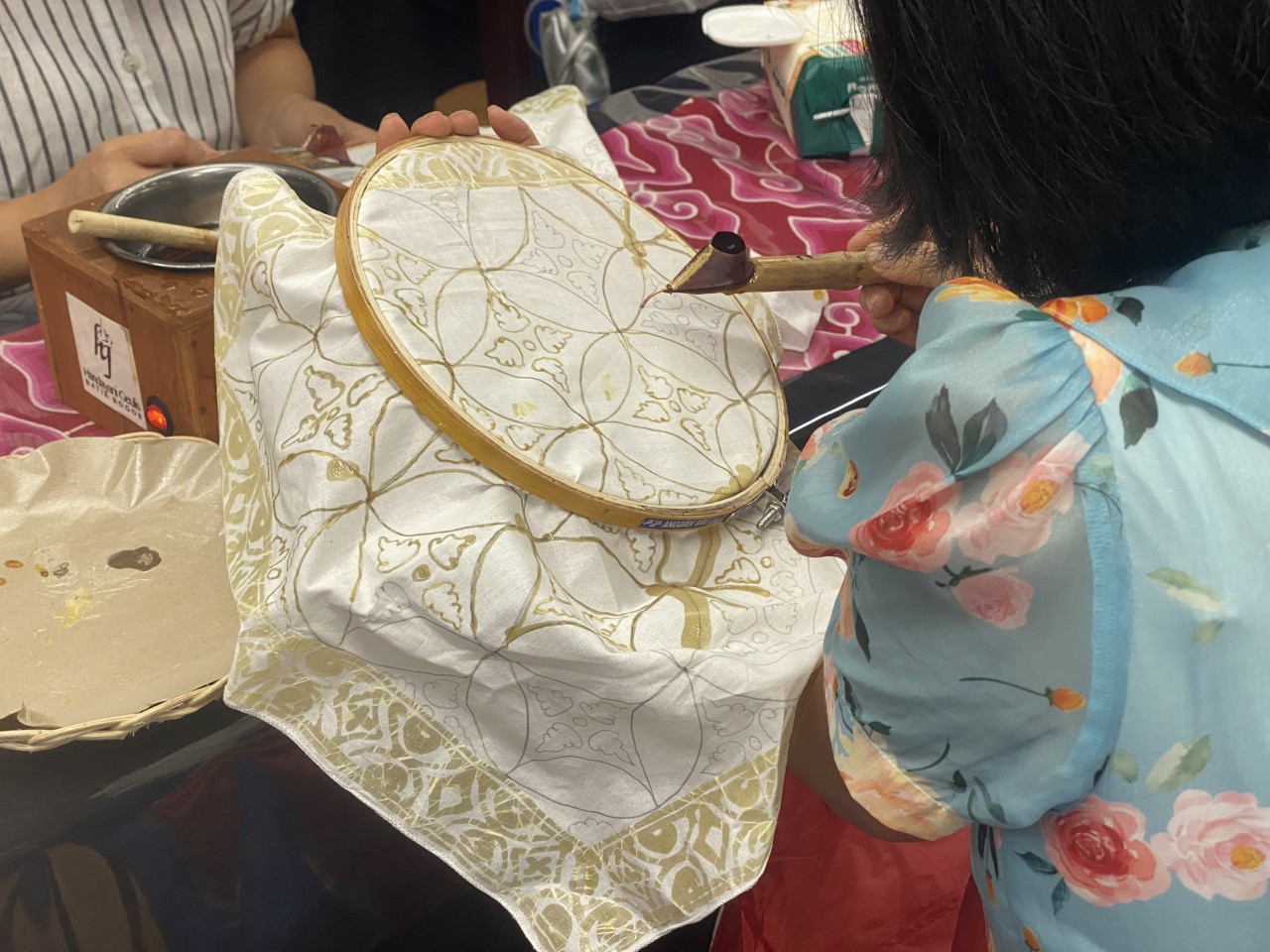 Khi vẽ, vải được căng lên một khung thêu. Người vẽ cầm khung vải đặt nghiêng góc 45 độ, cầm bút nghiêng góc 30 độ. Mỗi lần múc sáp chỉ nên múc từng chút một để sáp không bị nguội sau đó đưa từ từ chậm rãi để sáp chảy đều theo các đường nét đã được phác từ trước. Làm sao để đường sáp liền không bị đứt đòi hỏi sự tỉ mỉ, khéo léo của chính người vẽ (Ảnh: Mai Anh).
