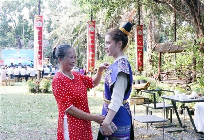 bà Lê Thị Minh Huệ, quận 10 chỉnh sửa trang phục cho người con đỡ đầu Lassamee Soulita, sinh viên Đại học Y khoa Phạm Ngọc Thạch Thành phố Hồ Chí Minh trước giờ khi lên biểu diễn văn nghệ. (Ảnh: TTXVN)
