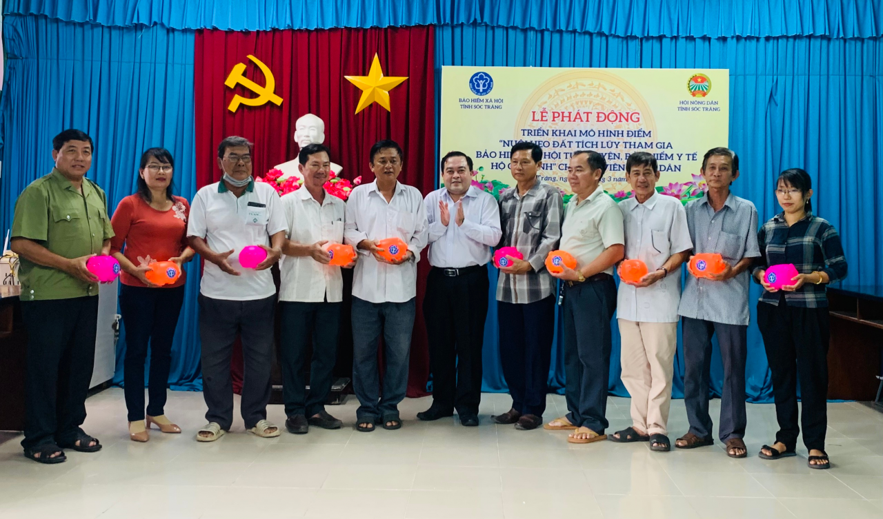 Ông Lâm Thanh Thiên - Phó Giám đốc BHXH tỉnh (thứ 6 từ phải sang) trao tặng heo đất cho hội viên nông dân tham gia mô hình (Ảnh: TL).