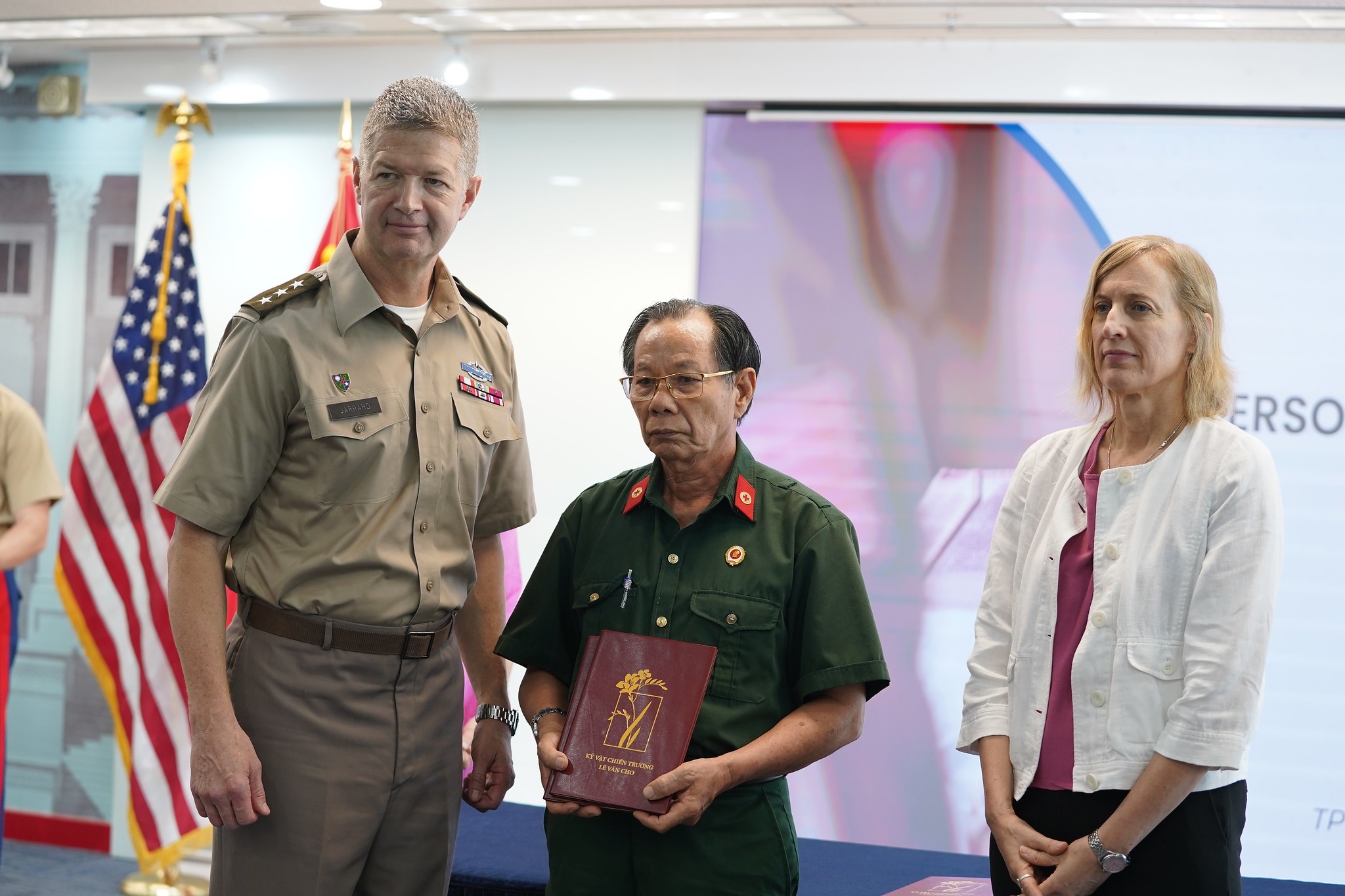 Ông Trần Văn Bản nhận kỷ vật của các đồng đội từ Trung tướng Mỹ James Jarrard ngày 24-5 Ông Trần Văn Bản nhận kỷ vật của các đồng đội từ Trung tướng Mỹ James Jarrard ngày 24-5