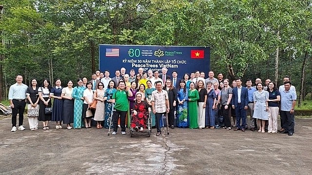 Friends of Vietnamese and the US join a group photo session in celebration of the 30th anniversary of PeaceTrees Vietnam (PTVN). (Photo: VNS) Friends of Vietnamese and the US join a group photo session in celebration of the 30th anniversary of PeaceTrees Vietnam (PTVN). (Photo: VNS)