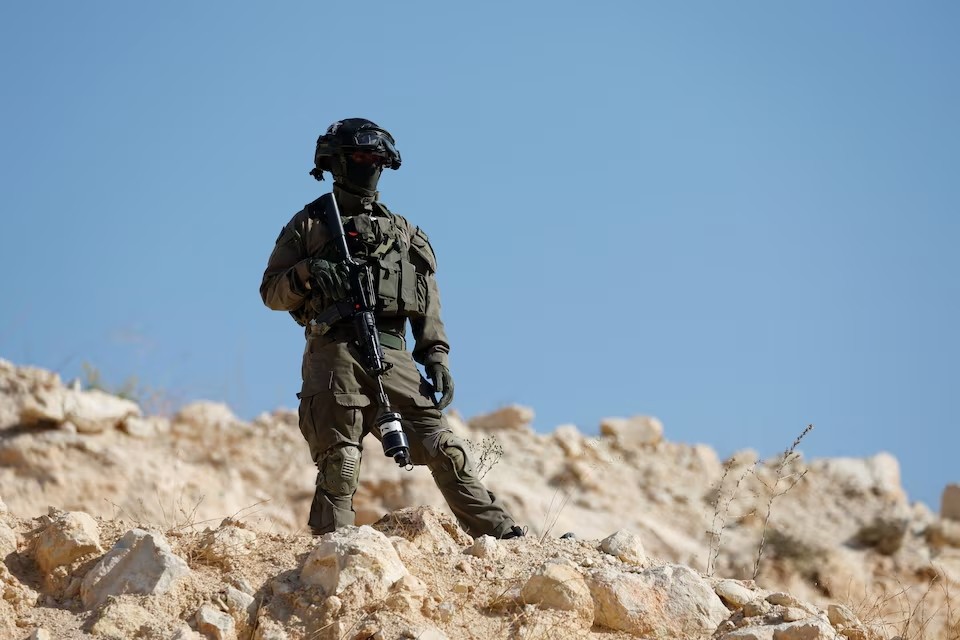 Một binh sĩ Israel đứng gác khi lực lượng Israel chặn đường người Palestine và các nhà hoạt động quốc tế đến khu vực thu hoạch ô liu gần Hebron, Bờ Tây bị chiếm đóng, ngày 23/10/2025. Ảnh: Reuters