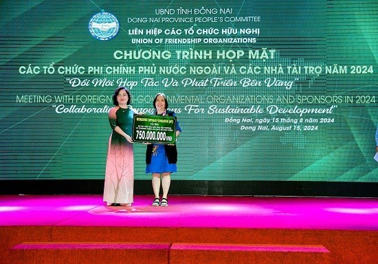 Vice President of the Dong Nai Union of Friendship Organizations Vy Vu Hong Thao receives a symbolic sponsorship plaque from WWO (USA). (Photo: dufo.dongnai.gov.vn)