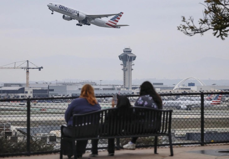 Một chiếc máy bay của American Airlines cất cánh gần tháp kiểm soát không lưu tại sân bay quốc tế Los Angeles - Ảnh: AFP