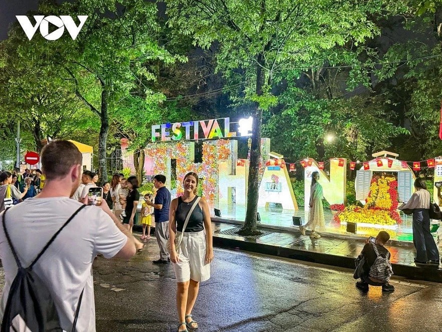 Foreign tourists pose for a photo at Hanoi Autumn Festival on Hoan Kiem pedestrian street.