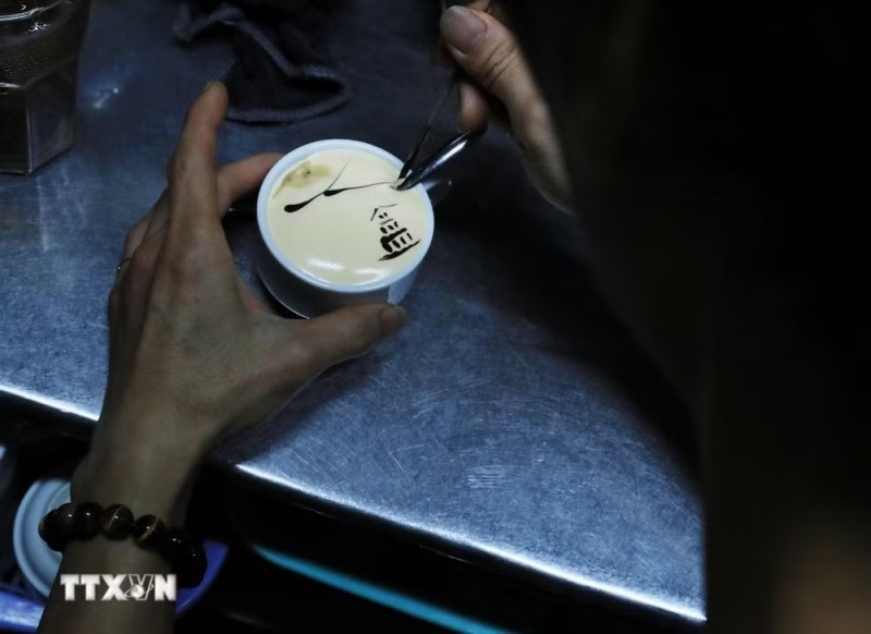 A barista decorates a cup of egg coffee with an image of Turtle Tower. (Photo: Lam Khanh/VNA) A barista decorates a cup of egg coffee with an image of Turtle Tower. (Photo: Lam Khanh/VNA)