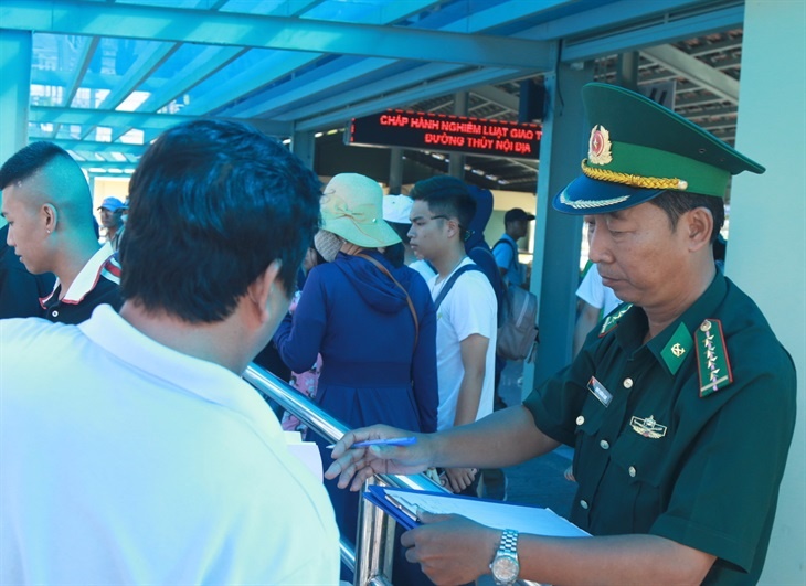 Đại úy Đinh Trường Nam, nhân viên Trạm kiểm soát Biên phòng cảng du lịch Cửa Bé, Đồn Biên phòng cửa khẩu cảng Nha Trang hướng dẫn các tàu đưa đón khách an toàn (Ảnh: Hải Luận) dai uy dinh truong nam nhan vien tram kiem soat bien phong cang du lich cua be don bien phong cua khau cang nha trang huong dan cac tau dua don khach an toan anh hai luan