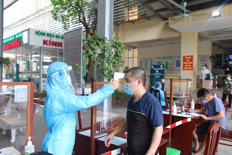 Cán bộ y tế đo thân nhiệt cho người đến khám bệnh Cán bộ y tế đo thân nhiệt cho người đến khám bệnh