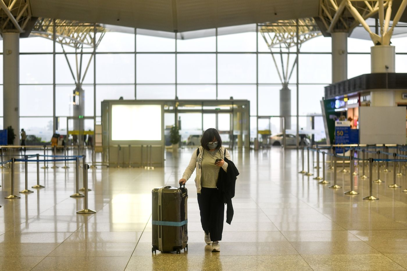 A passenger wearing a face mask walks in the nearly empty departure hall of Noi Bai International Airport in Hanoi on March 12. Photographer: Manan Vatsyayana/AFP via Getty Images 5114 1400x 1