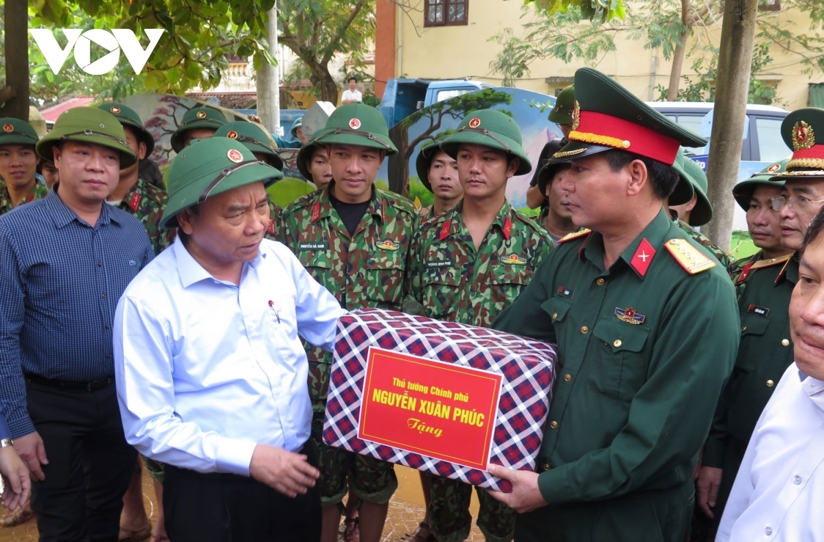PM calls for emergency aid to flood victims in central region PM phuc highlights the great efforts put in by relevant forces from ministry of national defence and public security as they participate relief rescue to protect lives property local citizens. pictured is pm presenting gifts officers soldiers military region 4