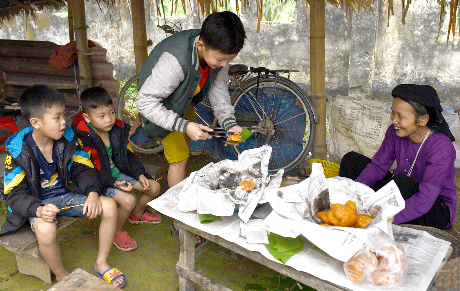 Một người phụ nữ Tày đang bán bánh rán cho những đứa trẻ. Một người phụ nữ Tày đang bán bánh rán cho những đứa trẻ.
