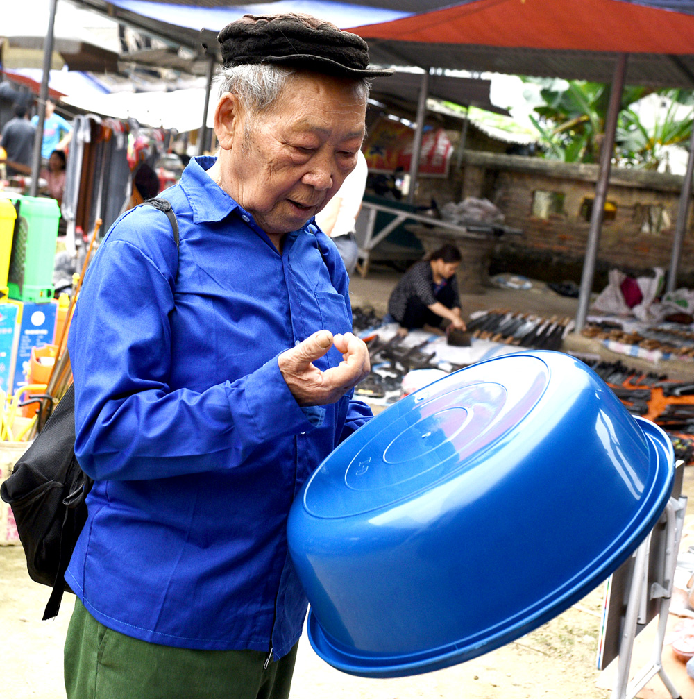 Người đàn ông Mông đang kiểm tra chất lượng chiếc chậu nhựa mà ông muốn mua Người đàn ông Mông đang kiểm tra chất lượng chiếc chậu nhựa mà ông muốn mua