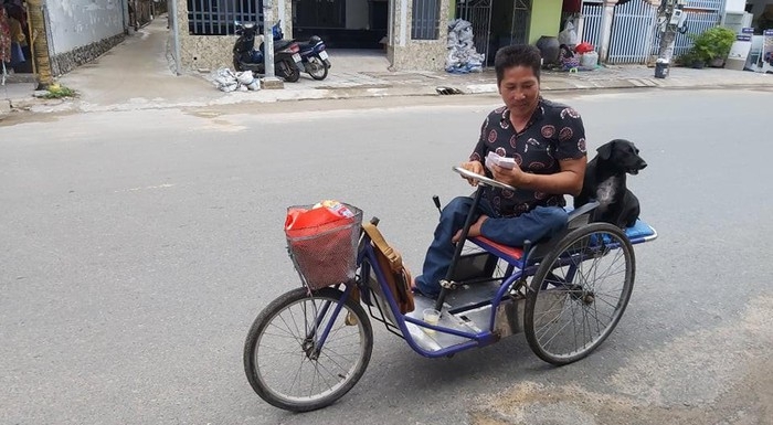 Dog helps Vietnamese handicapped owner sell lottery ticket, pick up charitable rice dog with lottery tickets on mouth helps handicapped owner earn a livelihood