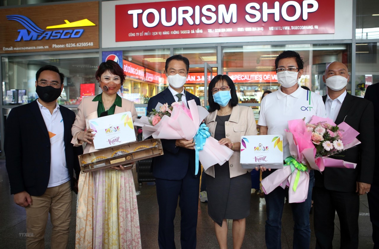 Phó Giám đốc Trung tâm Xúc tiến Du lịch Đà Nẵng Huỳnh Thị Hương Lan (giữa) tặng hoa và quà lưu niệm cho đại diện đoàn khách MICE. (Ảnh: Trần Lê Lâm/TTXVN)