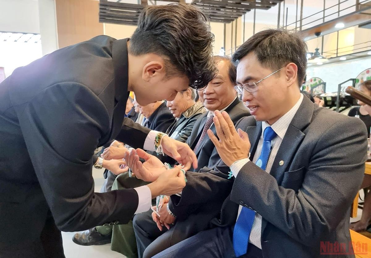 Các sinh viên Lào thực hiện lễ buộc chỉ cổ tay cho những người tham dự. (Ảnh: Báo Nhân Dân)