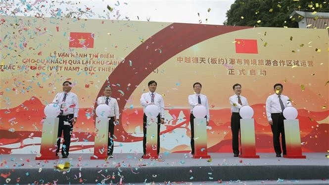双边省区领导人按下启动按钮，开始试运行接待游客来参观板约瀑布景观区。（图：越通社）