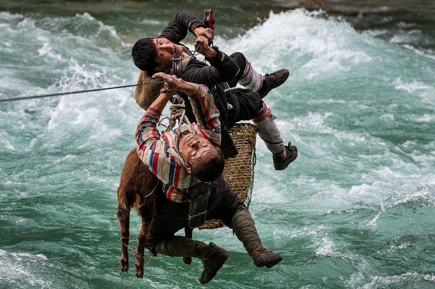 Two men use a zipline to transport animals and good across the river in Yunnan, China, May 2021. Photo by Minqiang Lu/The Nature Conservancy Two men use a zipline to transport animals and good across the river in Yunnan, China, May 2021. Photo by Minqiang Lu/The Nature Conservancy