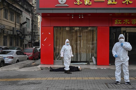 Officials in protective suits checking on an elderly man wearing a facemask who collapsed and died on a street near a hospital in Wuhan on Jan. 30 last year. Hector Retamal / AFP - Getty Images file 3908 210129 who wuhan mc 9304 8bd724c7bb1687f89bae7a5780e27a63fit 560w