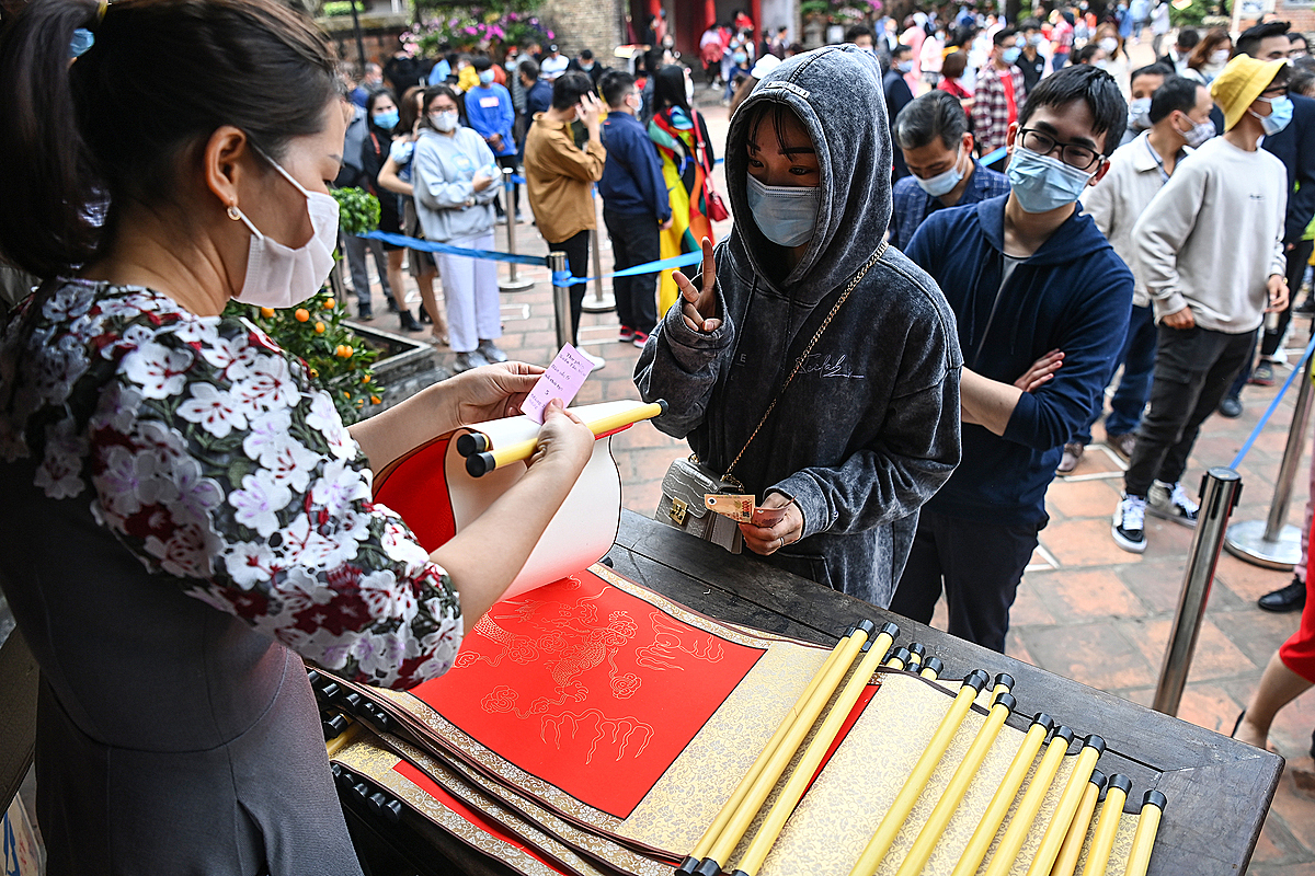 People lined up to be blessed with calligraphy in red or yellow do paper that costs VND100,000 ($4.4) a piece. (Photo: VnExpress) 2351 vanmieu vnexpress8 1613199480 5607 6707 1613208805