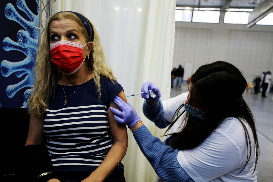 A woman receives a vaccination against the coronavirus disease (COVID-19) at a temporary Clalit healthcare maintenance organisation (HMO) centre, at a basketball court in Petah Tikva, Israel January 28, 2021. REUTERS/Ammar Awad A woman receives a vaccination against the coronavirus disease (COVID-19) at a temporary Clalit healthcare maintenance organisation (HMO) centre, at a basketball court in Petah Tikva, Israel January 28, 2021. REUTERS/Ammar Awad