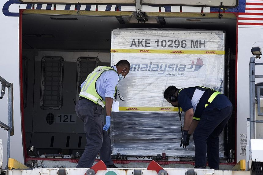 Containers carrying Pfizer-BioNTech Covid-19 vaccines being unloaded from a Malaysia Airlines plane at Kuala Lumpur International Airport yesterday, in a handout photo made available by Malaysia's Department of Information. Malaysian Prime Minister Muhyiddin Yassin and Director-General of Health Noor Hisham Abdullah will be the first to be inoculated.PHOTO: EPA-EFE 5922 batch