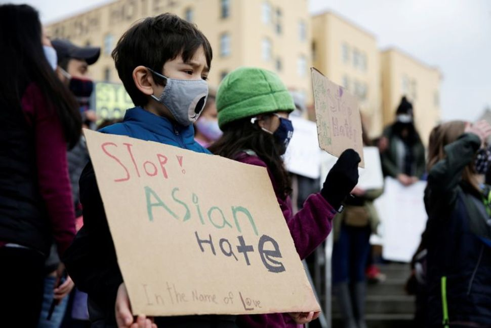 Zander Peterson, 8 and Aria Mingus-Shah, 8, hold signs during a Vietnamese family in Oakland violently robbed at home
