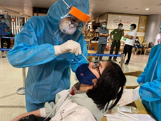 Health workers take samples for COVID-19 tests on an employee at Tân Sơn Nhất Airport on February 6. VNA/VNS Photo Đinh Hằng Health workers take samples for COVID-19 tests on an employee at Tân Sơn Nhất Airport on February 6. VNA/VNS Photo Đinh Hằng