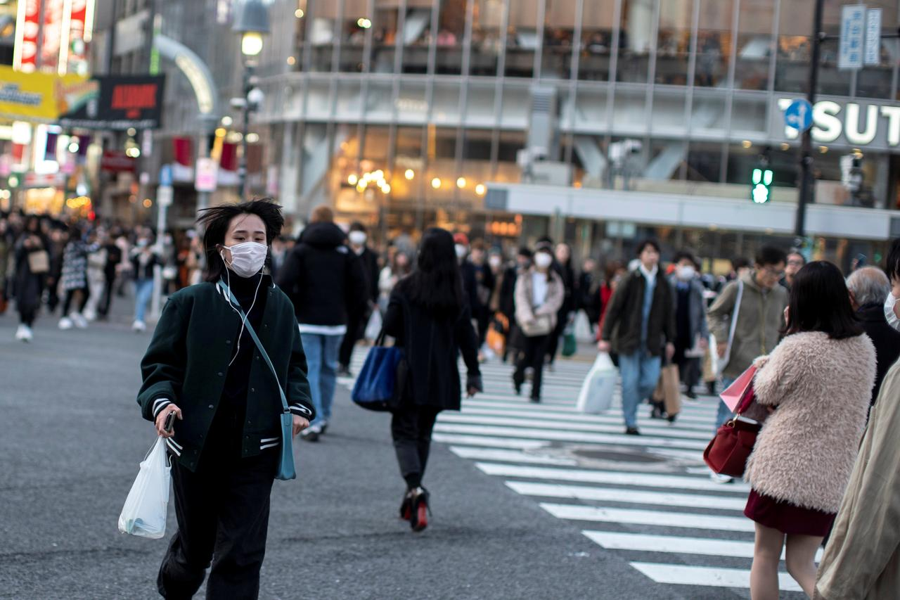 A woman wearing a protective face mask runs across a street at Shibuya in Tokyo, Japan, on February 17, 2020. Photo: Reuters 5055 japan 1