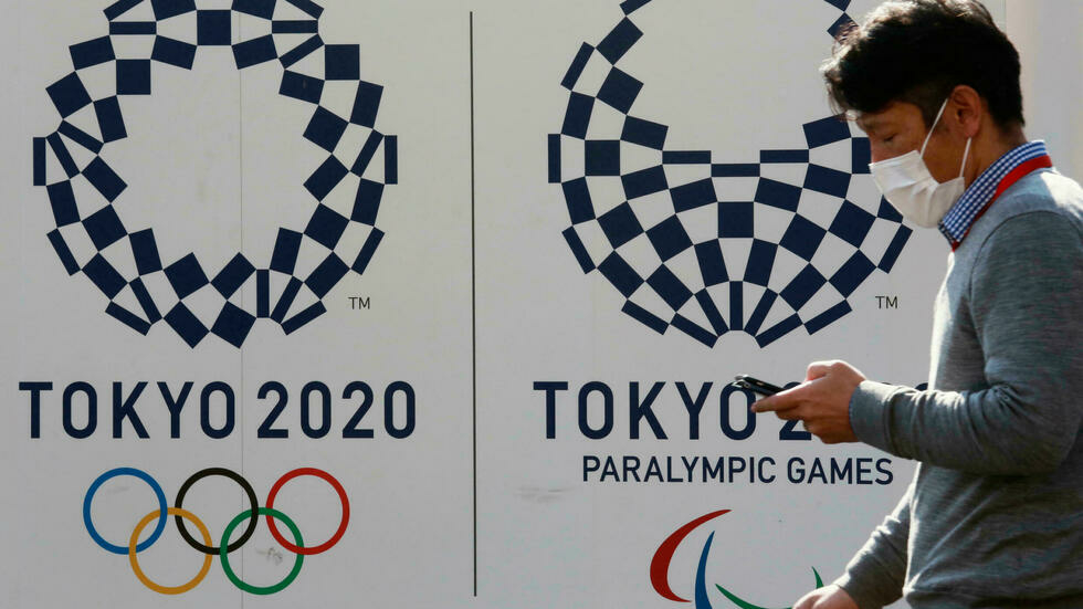 A man walks by logos of the Tokyo Olympic and Paralympic Games in Tokyo, Japan, February 1, 2021. © Koji Sasahara, AP A man walks by logos of the Tokyo Olympic and Paralympic Games in Tokyo, Japan, February 1, 2021. © Koji Sasahara, AP