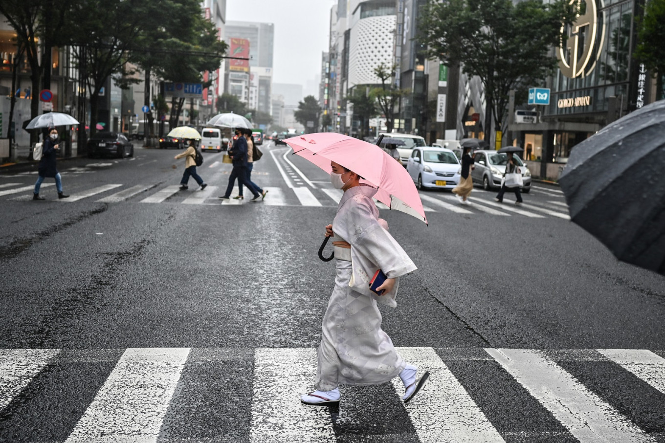 A woman wearing traditional dress uses an umbrella to shelter from the rain while crossing a street in Tokyo on September 24, 2020. (AFP/Charly Triballeau) 0908 japan