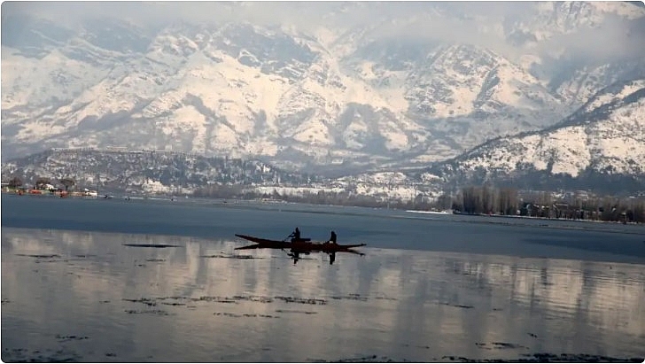 Kashmiri boatmen ride a boat in Dal Lake with the backdrop of snow-covered mountains in Srinagar on January 8. (Bilal Bahadur/TOI, BCCL, Delhi) 3042 india 262