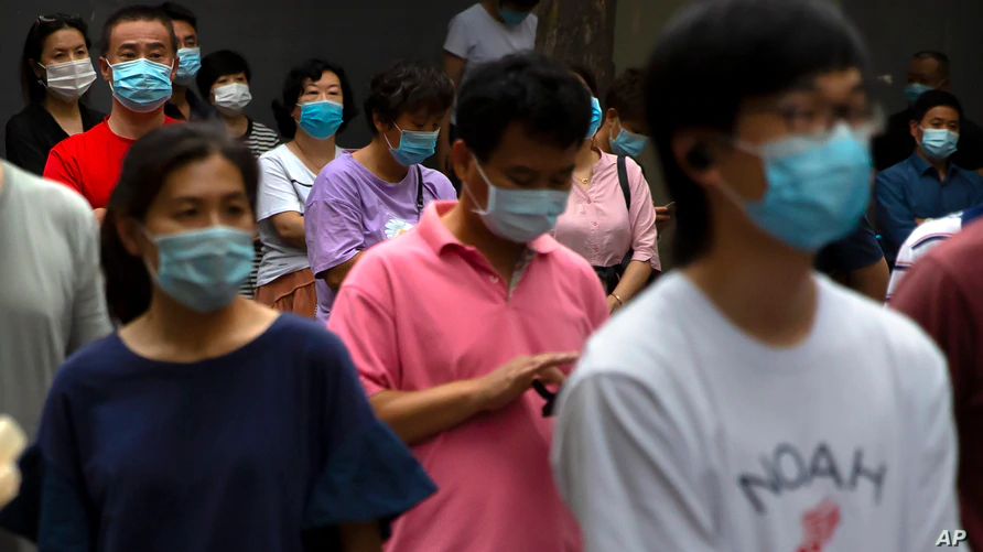 Parents and relatives wearing face masks to protect against the coronavirus wait for students to finish taking national college entrance exams on the final day of testing in China, July 10, 2020, in Beijing. 0708 who1