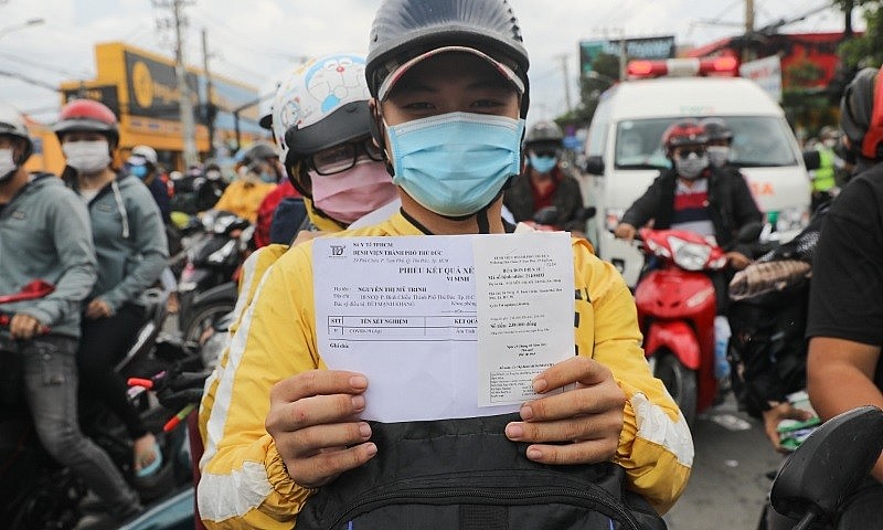 A motorbike driver holds up his Covid-19 test result in Ho Chi Minh City, Oct. 1, 2021. Photo by VnExpress A motorbike driver holds up his Covid-19 test result in Ho Chi Minh City, Oct. 1, 2021. Photo by VnExpress