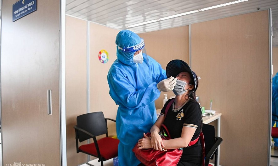 A health worker collects coronavirus test samples from a passenger at Hanoi's Noi Bai Airport. Photo by VnExpress A health worker collects coronavirus test samples from a passenger at Hanoi's Noi Bai Airport. Photo by VnExpress