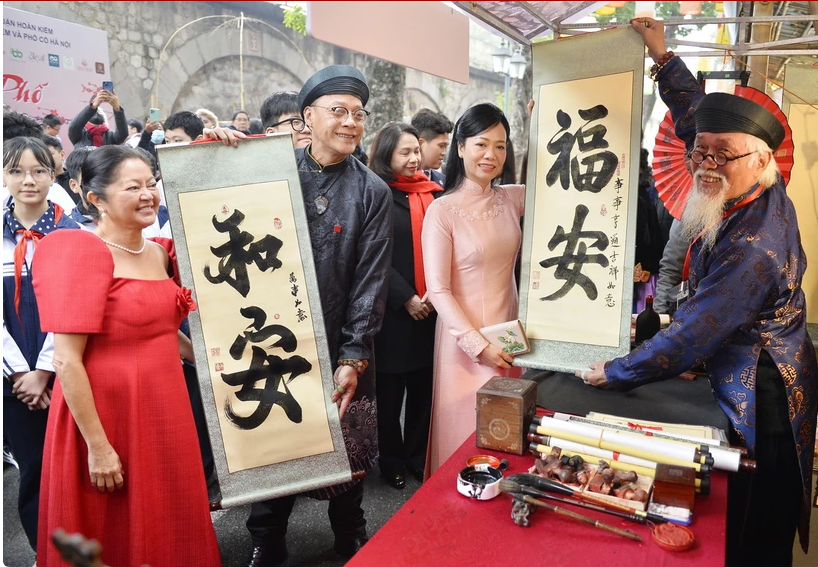 两位夫人来到冯兴街参观各个摆满年货的摊位,向书法家求字。 两位夫人来到冯兴街参观各个摆满年货的摊位,向书法家求字。