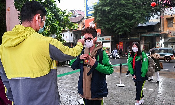 A school staff checks temperature of a student in Hanoi on February 8, 2022. Photo: VnExpress A school staff checks temperature of a student in Hanoi on February 8, 2022. Photo: VnExpress
