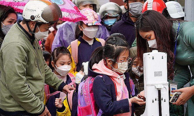 Hanoi first graders disinfect their hands and have their temperature checked before attending school for the first time, Feb. 10, 2022. Photo: VnExpress Hanoi first graders disinfect their hands and have their temperature checked before attending school for the first time, Feb. 10, 2022. Photo: VnExpress