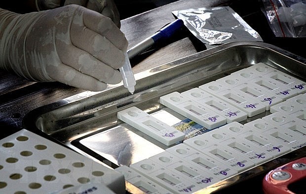 A medical worker places drops of liquid sample into a Covid-19 indicator device. Photo: VNA A medical worker places drops of liquid sample into a Covid-19 indicator device. Photo: VNA