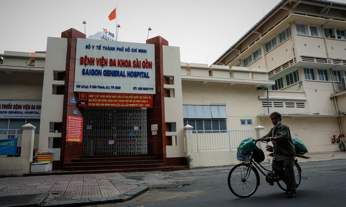 A man walks a bicycle past the Saigon General Hospital in HCMC's District, June 22, 2021. The hospital is currently locked down as linked to at least five Covid-19 cases. Photo: VnExpress A man walks a bicycle past the Saigon General Hospital in HCMC's District, June 22, 2021. The hospital is currently locked down as linked to at least five Covid-19 cases. Photo: VnExpress