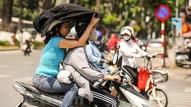 Motorcylists cover themselves with thick clothing to avoid the heat. Photo: VNA Motorcylists cover themselves with thick clothing to avoid the heat. Photo: VNA