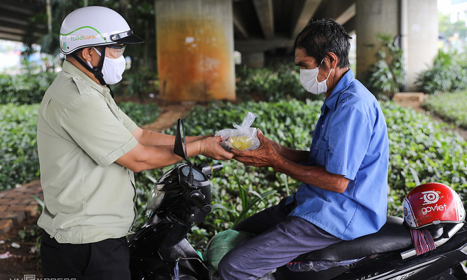 A motorbike taxi driver receives a charity meal in HCMC, July 2021. Photo: VnExpress A motorbike taxi driver receives a charity meal in HCMC, July 2021. Photo: VnExpress