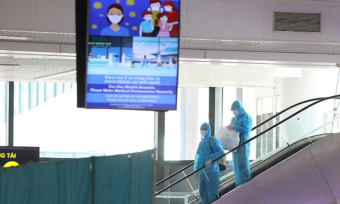 Two passengers wearing protective suits arrive at Hanoi's Noi Bai airport from HCMC, July 2021. Photo: VnExpress Two passengers wearing protective suits arrive at Hanoi's Noi Bai airport from HCMC, July 2021. Photo: VnExpress
