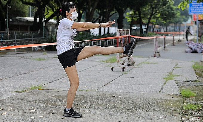 A woman does morning exercise at a park in HCMC, October 1, 2021. Photo: VnExpress A woman does morning exercise at a park in HCMC, October 1, 2021. Photo: VnExpress