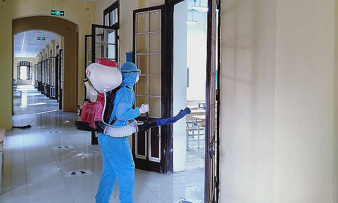 A staff member disinfects a classroom at Hanoi's Phan Dinh Phung High School, preparing for the return of students, Dec. 3, 2021. Photo: VnExpress A staff member disinfects a classroom at Hanoi's Phan Dinh Phung High School, preparing for the return of students, Dec. 3, 2021. Photo: VnExpress