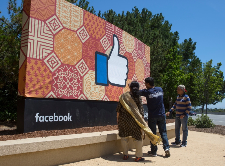 Visitors visit the sign outside Facebook headquarters at 1 Hacker Way, in Menlo Park, Calif., Friday, May 27, 2016. Tech tourism has become prevalent in the past few years at Silicon Valley icons. (Patrick Tehan/Bay Area News Group) 5219 sjm facesign xxxx 05